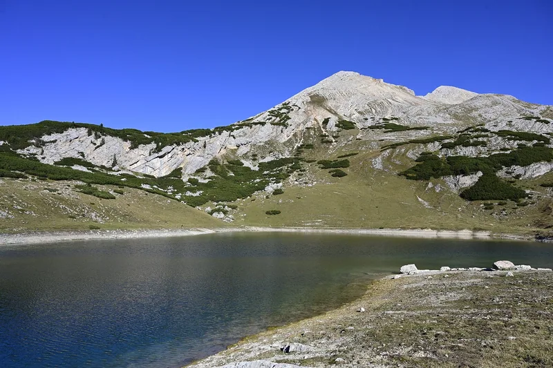 Lago di Limo, et lite fjellvann på platået i Fanes-Sennes-Prags naturpark, under en lys, delvis gresskledd fjelltopp.