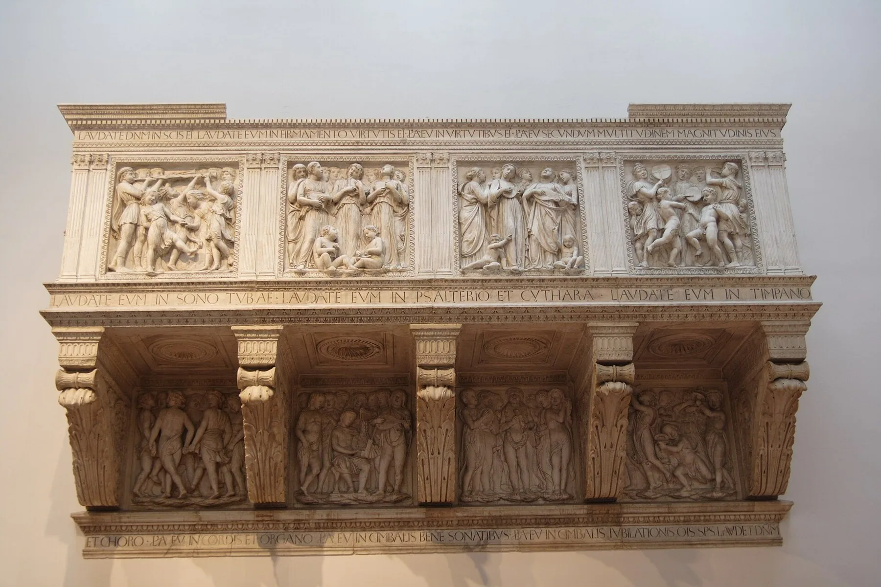 Luca della Robbias sangtribune i hvit marmor, med relieffer av musikere, sangere og dansende barn og latinske innskrifter langs kantene.