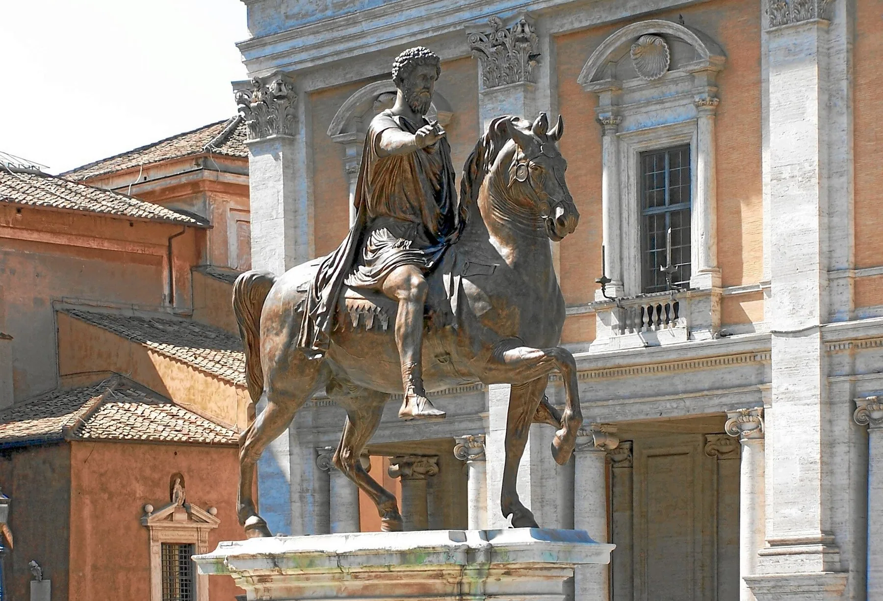Bronserytterstatuen av Marcus Aurelius med utstrakt arm på Kapitol-plassen, foran en palassfasade i lys stein.