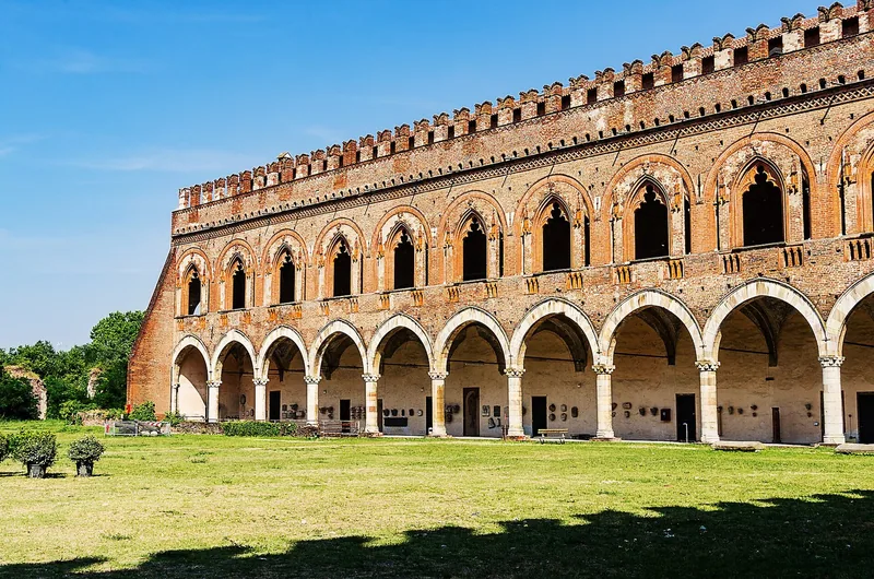 Borggården i Castello Visconteo i Pavia med lange buerekker i første etasje og gotiske vinduer i rød tegl over.