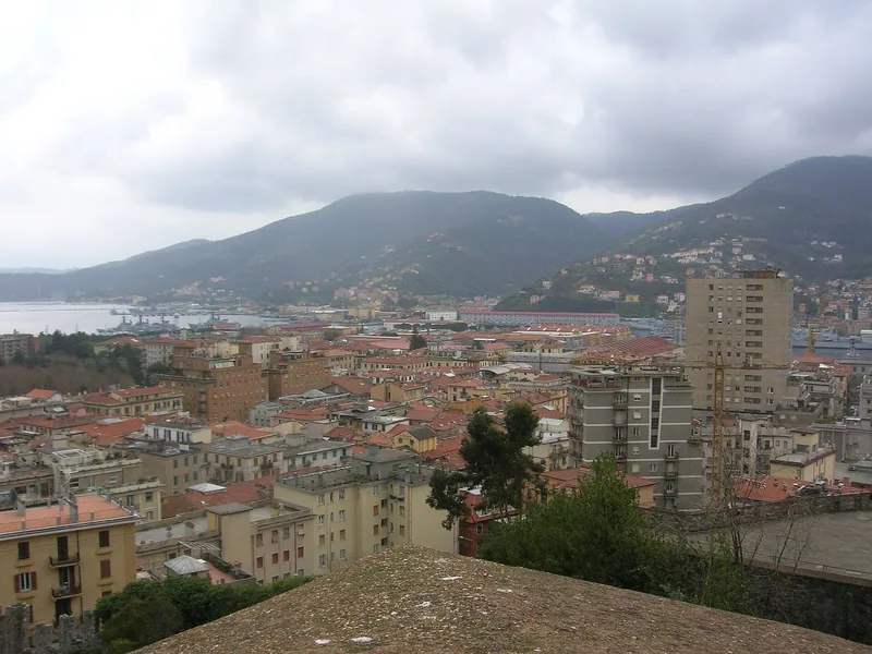 Utsikt fra borgen over hustakene i La Spezia ned mot havnebukta, med fjellene på den andre siden.