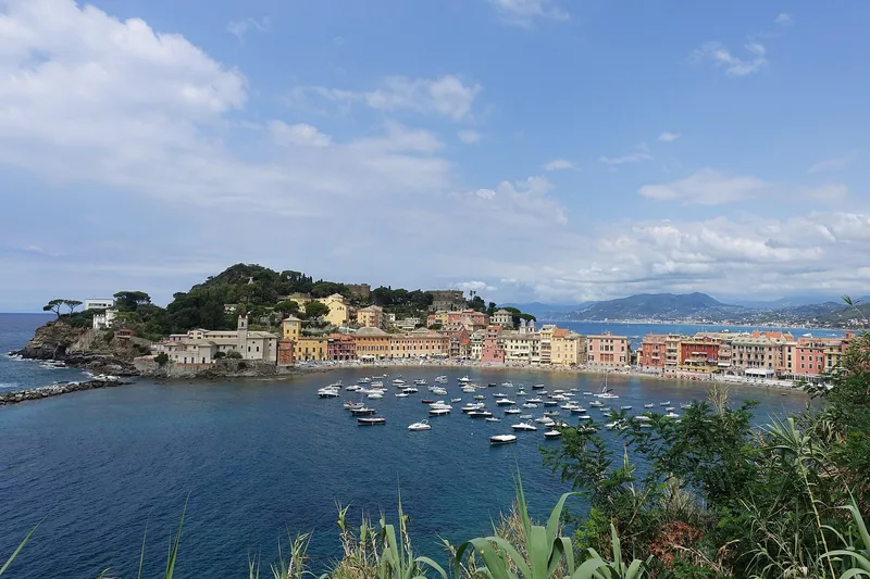 Baia del Silenzio i Sestri Levante, en rolig bukt med små båter foran fargerike hus og en skogkledd halvøy.