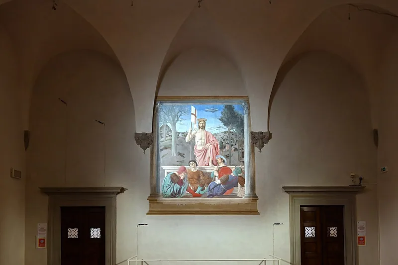 Pieros freske Oppstandelsen på en hvit vegg under hvelvbuer i museet i Sansepolcro, med Kristus stående over graven og sovende soldater foran.