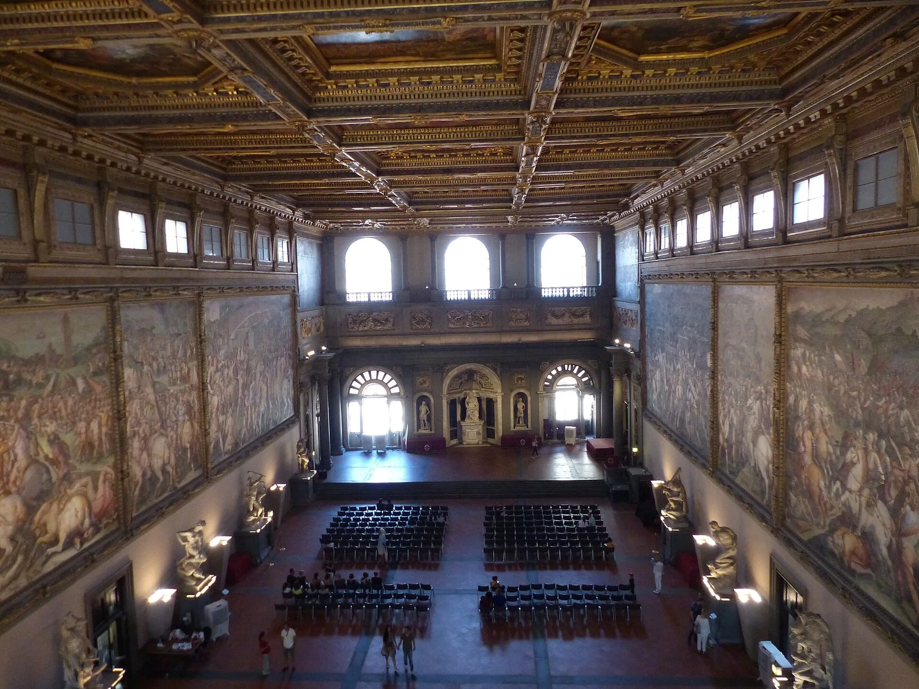 Salone dei Cinquecento i Palazzo Vecchio sett ovenfra, med Vasaris store slagscener på veggene, et forgylt kassettak og stoler satt opp i salen.