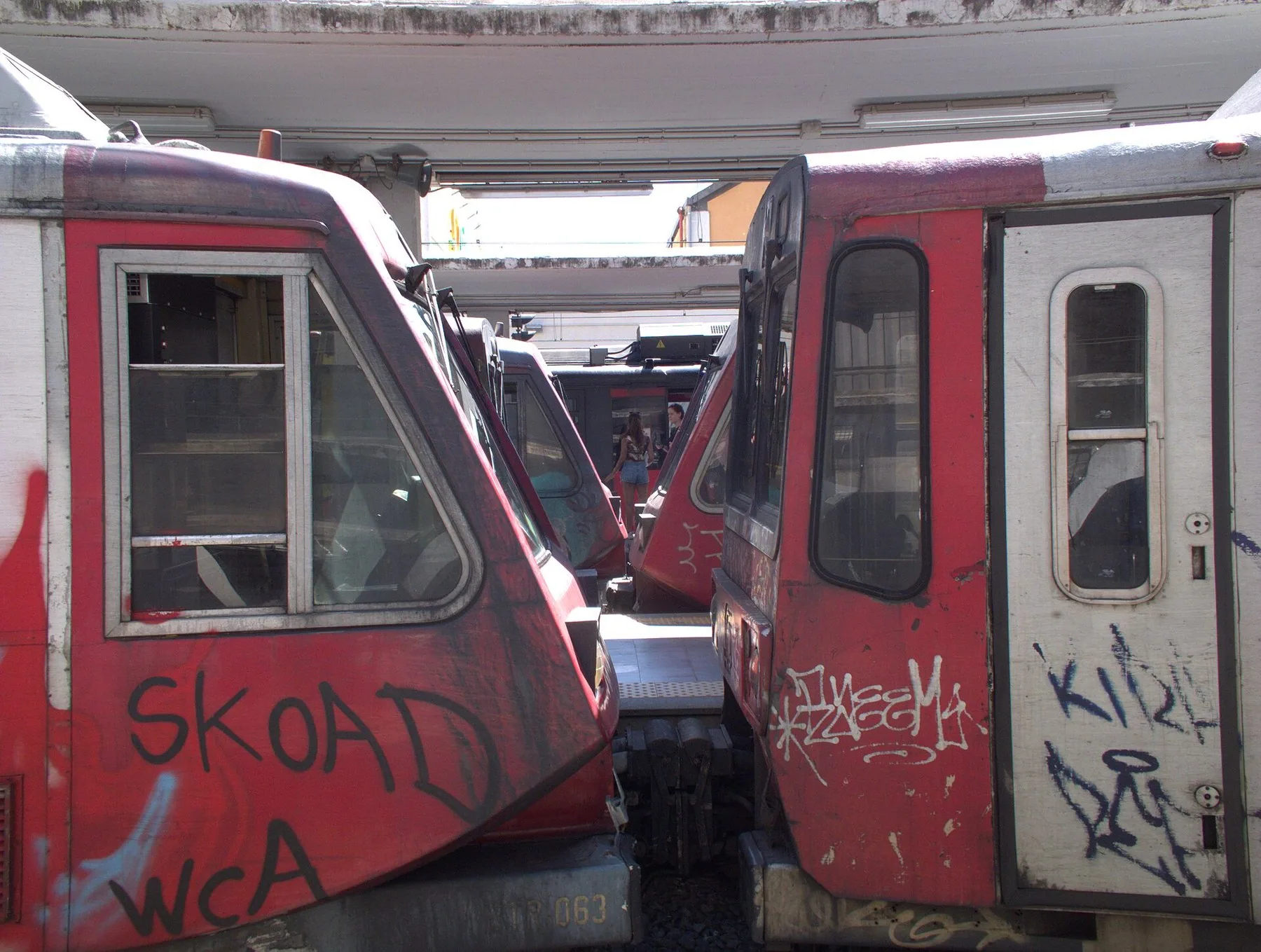 Gamle røde lokaltog dekket av graffiti står side om side på endestasjonen i Napoli.