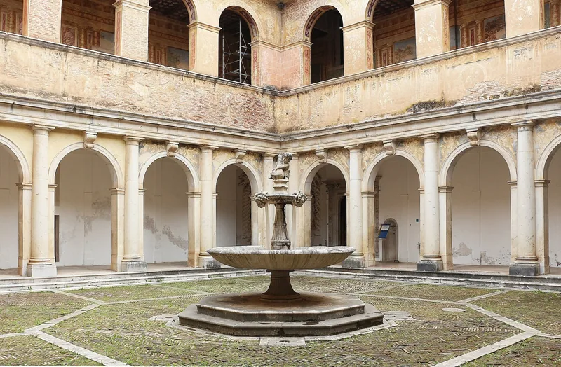 Den store klostergården i Certosa di San Lorenzo, med en brønn midt på plenen omgitt av to etasjer med buer.