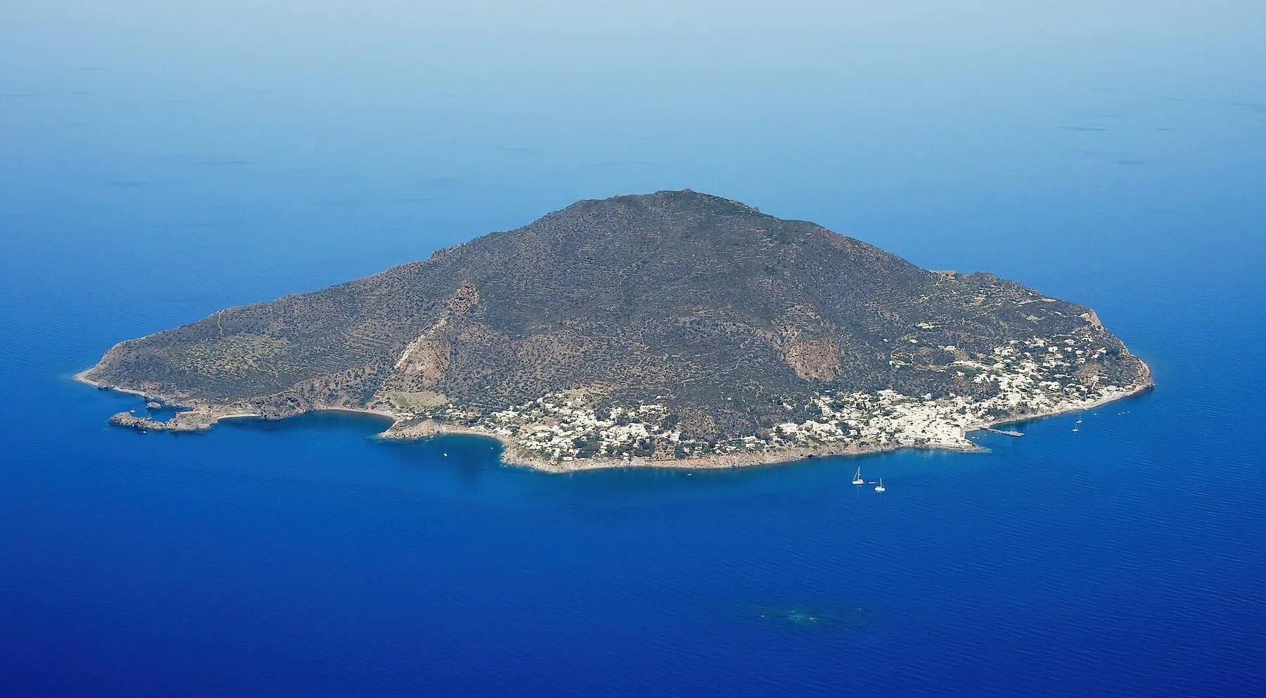 Panarea sett fra lufta, en liten vulkanøy med hvite hus langs kysten og dypblått hav rundt.