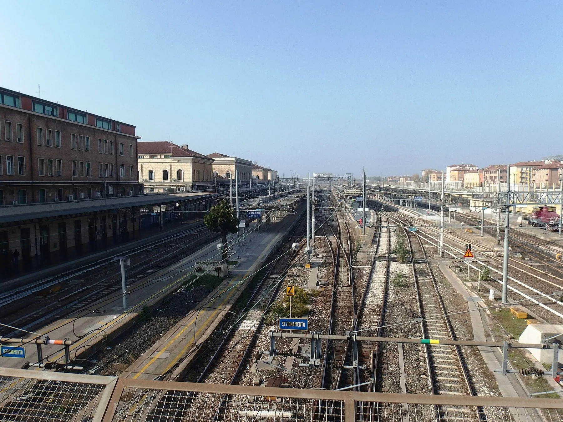 Sporområdet på Bologna Centrale sett ovenfra, med plattformer, kontaktledninger og stasjonsbygningene langs sporene.